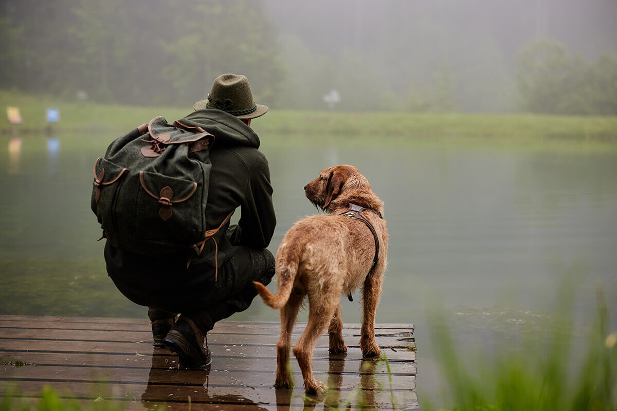 Jäger mit Hund beim Blick über den See